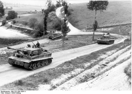 Click to view full size image
 ============== 
Tiger I heavy tanks of the German 1st SS Division Leibstandarte SS Adolf Hitler on a country road in Northern France, spring 1944, photo 2 of 2.

Source: German Federal Archive
